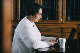 Woman Working on a Laptop with a Cup of Coffee at the Table  image 4