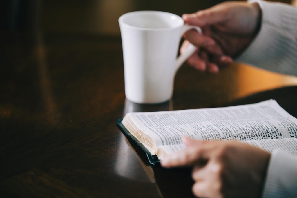 Woman Reading the Bible and Drinking Coffee at a Table large preview