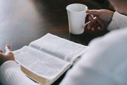 Woman Reading the Bible and Drinking Coffee at a Table  image 1