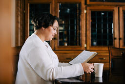 Woman Reading the Bible and Drinking Coffee at a Table  image 3