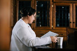 Woman Reading the Bible and Drinking Coffee at a Table  image 1