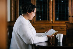 Woman Reading the Bible and Drinking Coffee at a Table  image 2