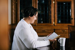 Woman Reading the Bible and Drinking Coffee at a Table  image 4