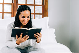 Woman Reading the Bible in Bed at Sunrise  image 1