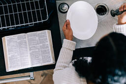 Woman Doing Dishes with the Bible Open Next to Her on the Counter  image 3