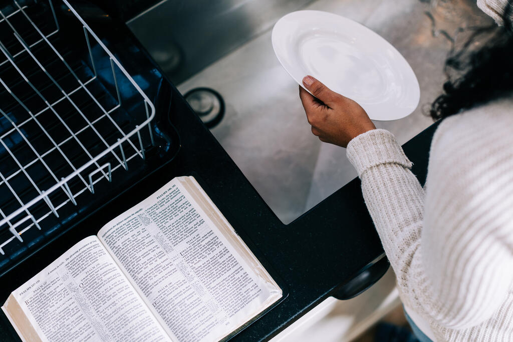 Woman Doing Dishes with the Bible Open Next to Her on the Counter large preview