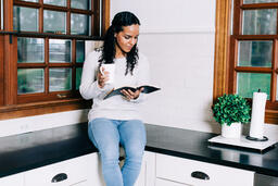 Woman Reading the Bible and Drinking Coffee in the Kitchen  image 1