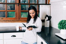 Woman Reading the Bible and Drinking Coffee in the Kitchen  image 2