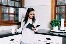 Woman Reading the Bible and Drinking Coffee in the Kitchen  image 1