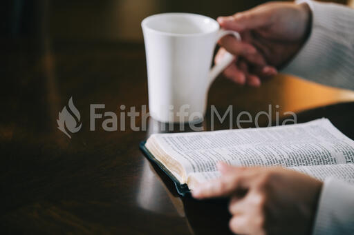 Woman Reading the Bible and Drinking Coffee at a Table