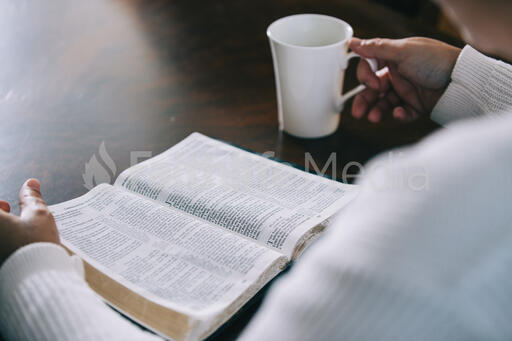 Woman Reading the Bible and Drinking Coffee at a Table