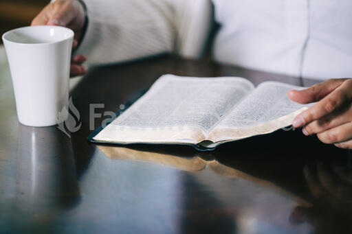 Woman Reading the Bible and Drinking Coffee at a Table