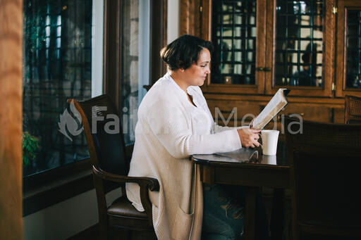 Woman Reading the Bible and Drinking Coffee at a Table