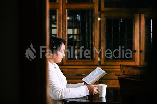 Woman Reading the Bible and Drinking Coffee at a Table