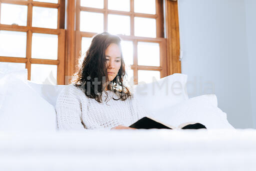 Woman Reading the Bible in Bed at Sunrise