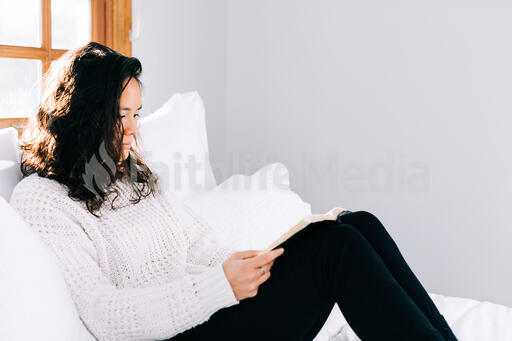 Woman Reading the Bible in Bed at Sunrise