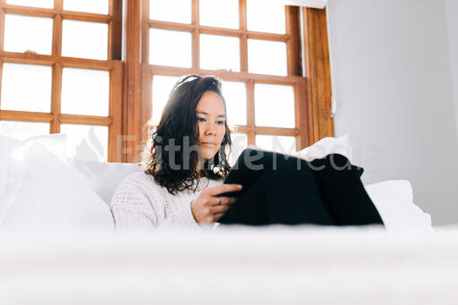 Woman Reading the Bible in Bed at Sunrise