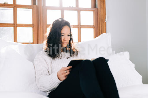 Woman Reading the Bible in Bed at Sunrise