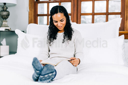 Woman Reading the Bible in Bed at Sunrise