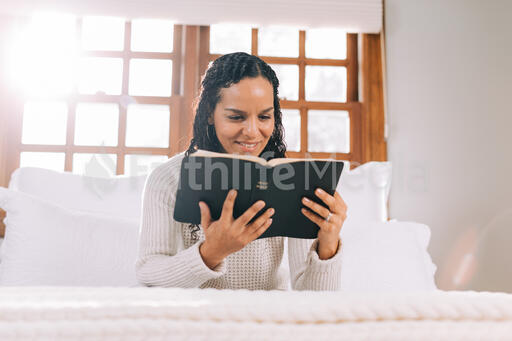 Woman Reading the Bible in Bed at Sunrise