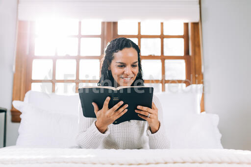 Woman Reading the Bible in Bed at Sunrise