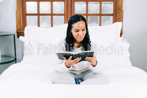 Woman Reading the Bible in Bed at Sunrise