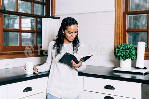 Woman Reading the Bible and Drinking Coffee in the Kitchen