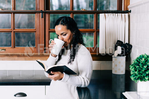 Woman Reading the Bible and Drinking Coffee in the Kitchen