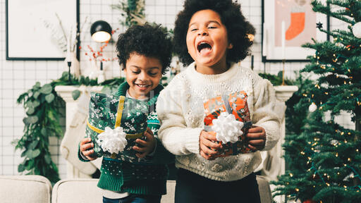 Children Jumping on the Sofa Holding Christmas Presents