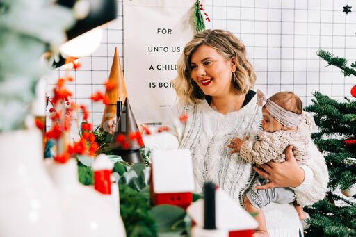 Woman Holding Her Baby and Decorating for Christmas