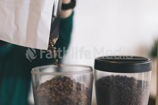 Barista Pouring Coffee Beans into a Grinder