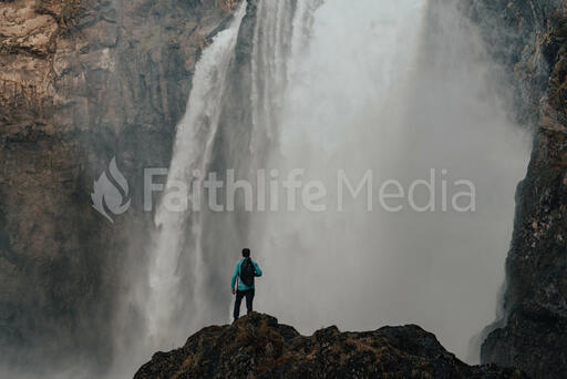 Hiker Standing in Front of a Waterfall