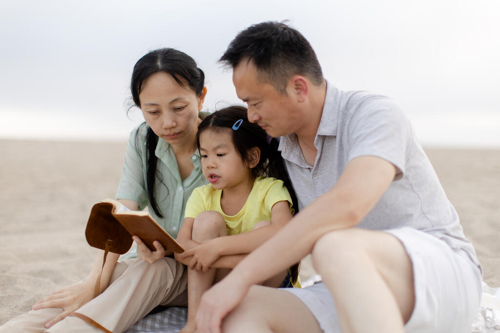 Family Reading the Bible Together on the Beach large preview
