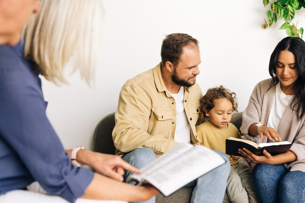 Young Family Reading the Bible with an Older Couple large preview