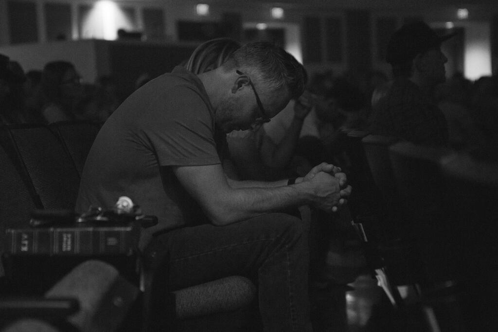 Man Bowing Head in Prayer During Church Service large preview