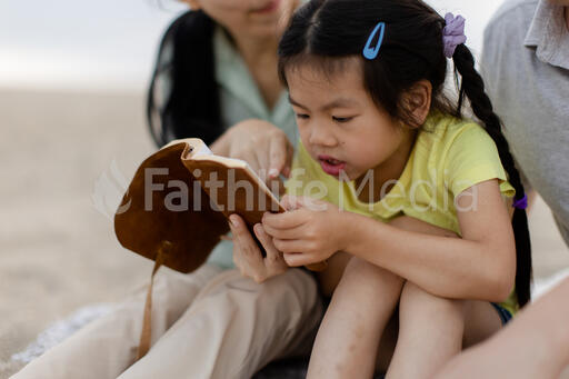 Family Reading the Bible Together on the Beach