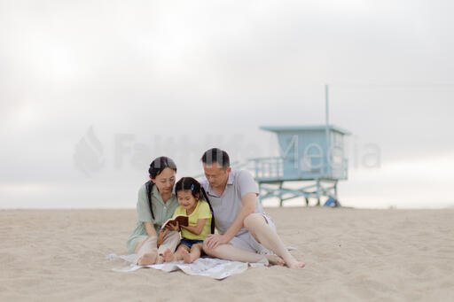 Family Reading the Bible Together on the Beach