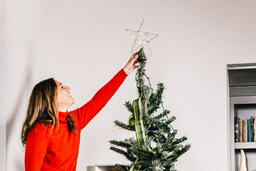 Woman Putting a Star Tree Topper on the Christmas Tree  image 2