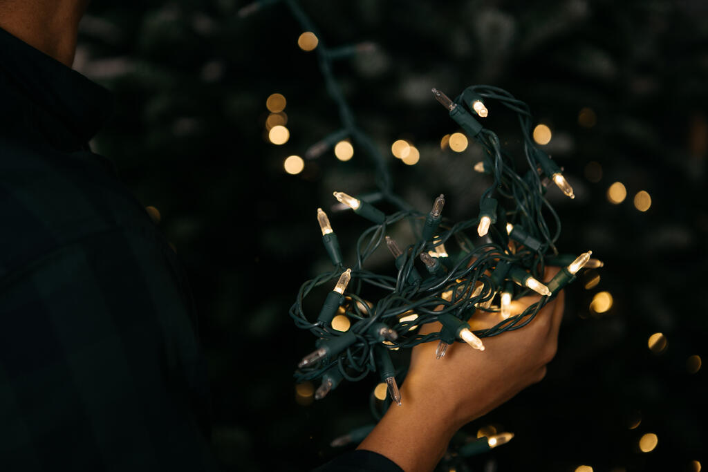 Man Putting Twinkle Lights on a Christmas Tree large preview