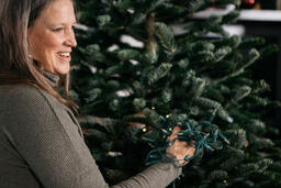 Woman with Gray Hair Decorating a Christmas Tree  image 1