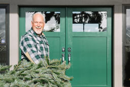 Man with Gray Hair Carrying a Christmas Tree into the House  image 2