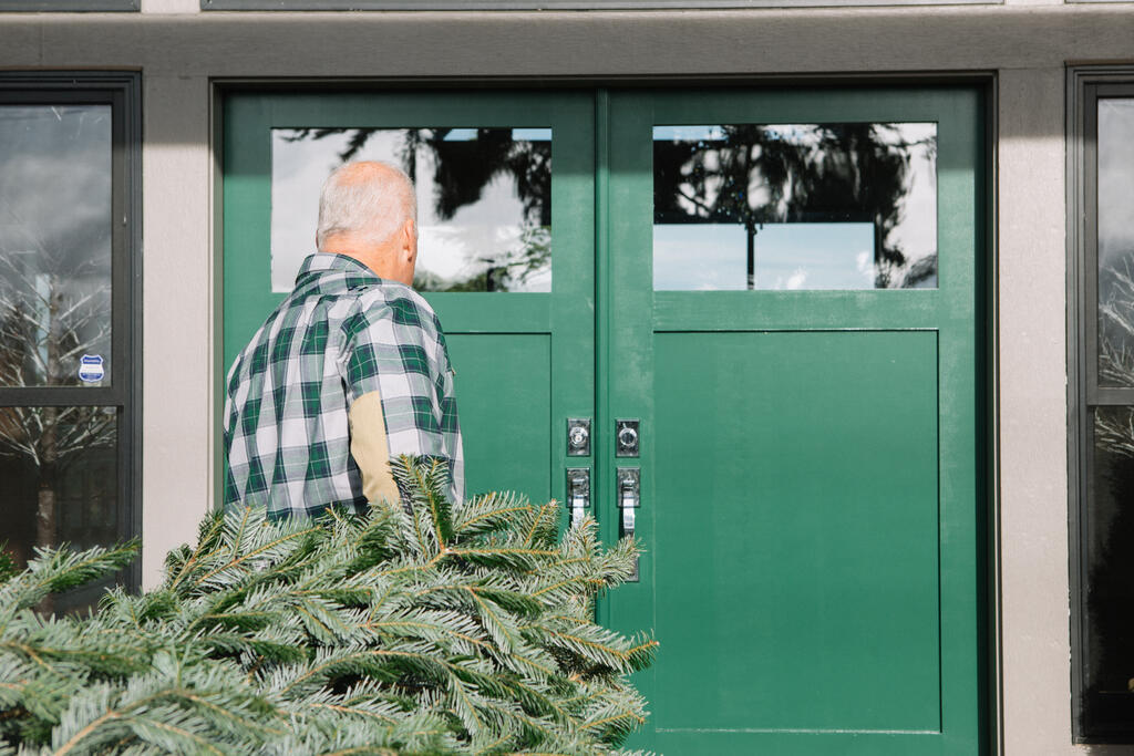 Man with Gray Hair Carrying a Christmas Tree into the House large preview