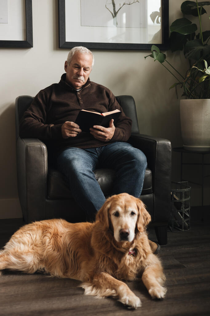 Senior Man Reading the Bible at Home with His Dog large preview