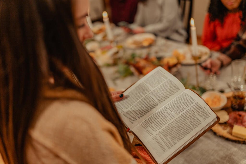 Woman Reading from the Bible before Thanksgiving Dinner large preview