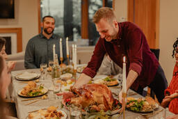 Man Placing the Thanksgiving Turkey on the Dinner Table  image 1