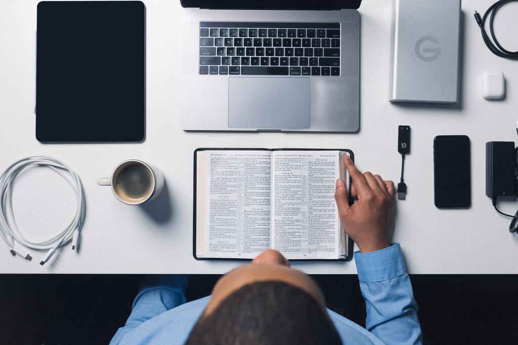 Seminary Student Reading the Bible Surrounded by Technology large preview