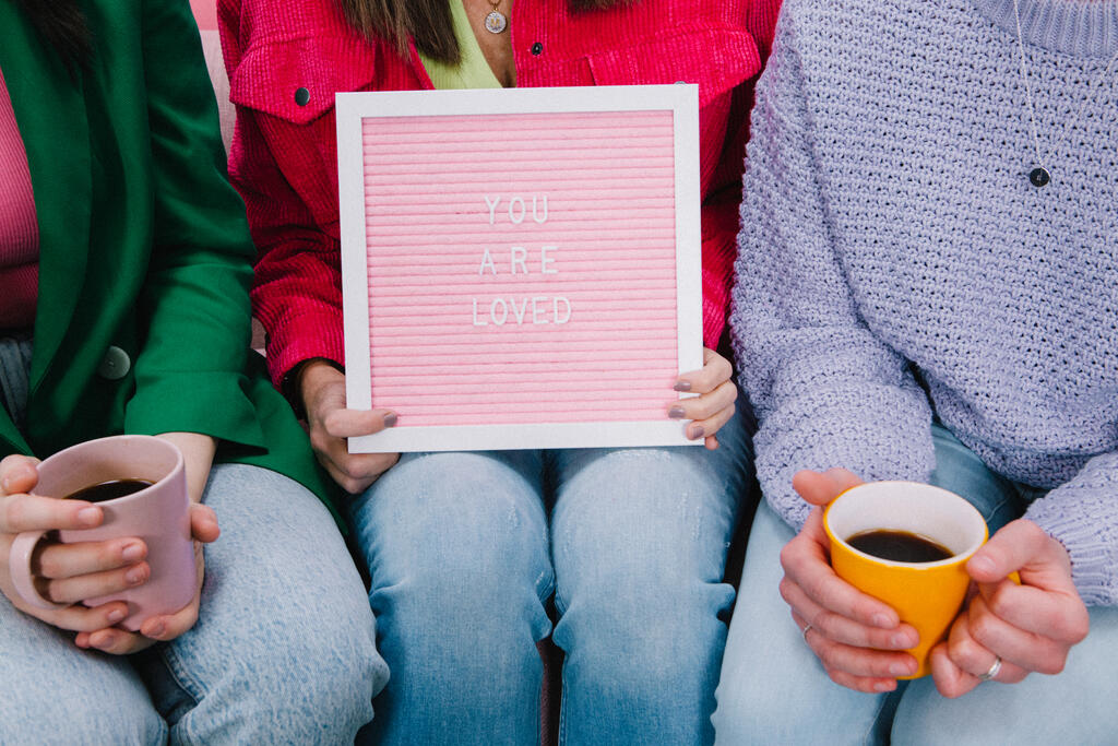 Women Holding a Pink Letter Board Reading YOU ARE LOVED large preview