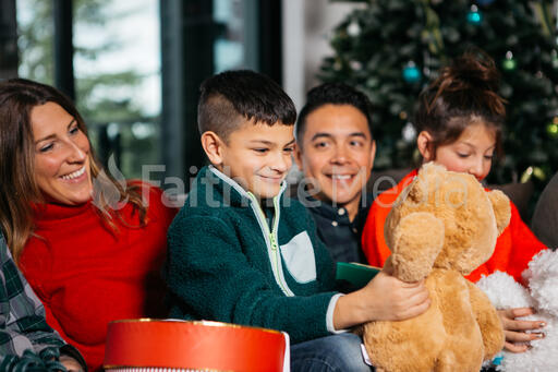 Young Family Opening Presents in Front of the Christmas Tree