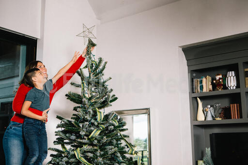 Mother and Son Putting a Star Tree Topper on the Christmas Tree