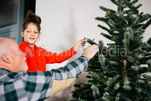 Grandpa and Granddaughter Decorating a Christmas Tree Together